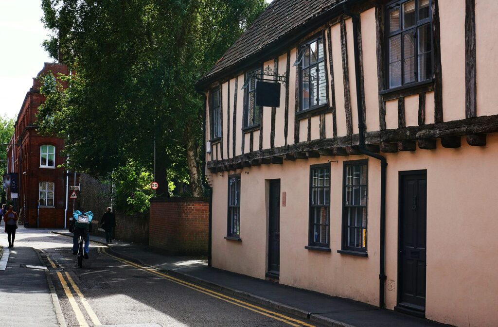 Explore a quaint street in Norwich featuring traditional timber-framed buildings, capturing historic charm.